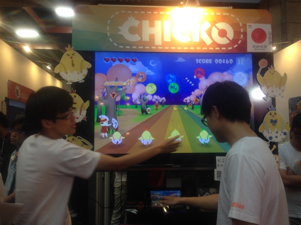 タッチパネルを使ったゲーム「CHICKO」の紹介をする学生