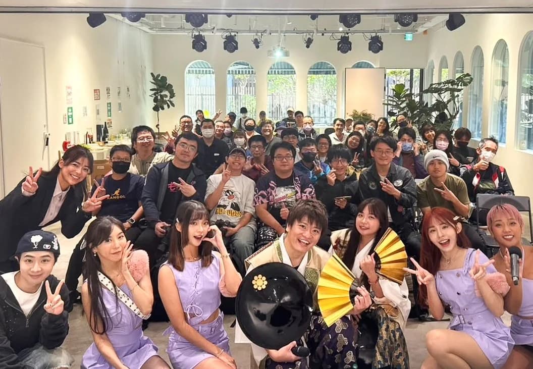 イベント会場での記念撮影。前列に和装と紫の衣装の出演者、後ろに大勢の来場者が並んでいる