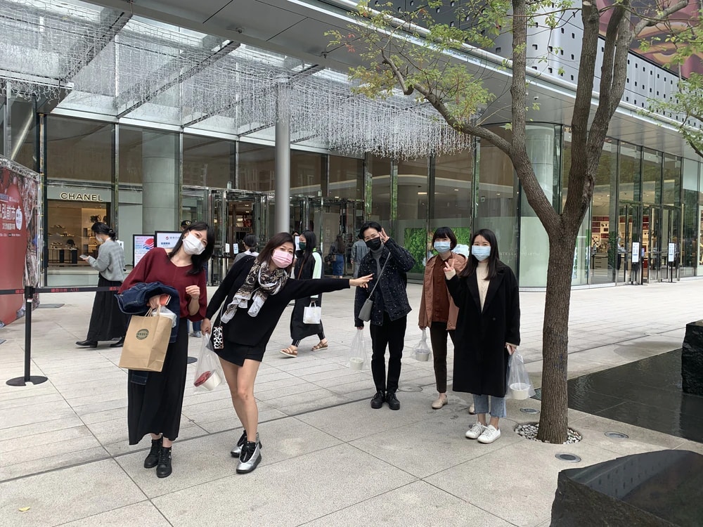 戴著口罩的五位成員,提著購物袋走在街上